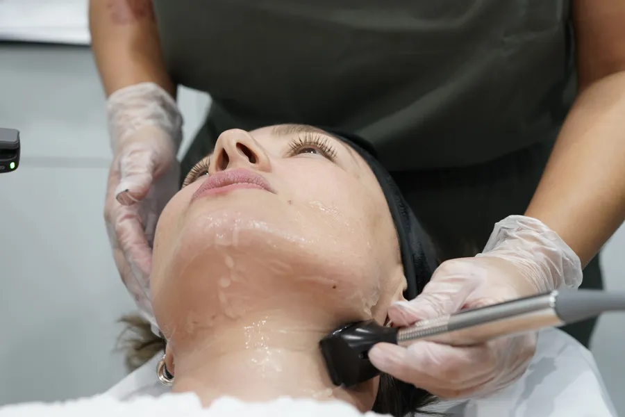 An AWE provider gliding the Forma handpiece along a guest's jaw