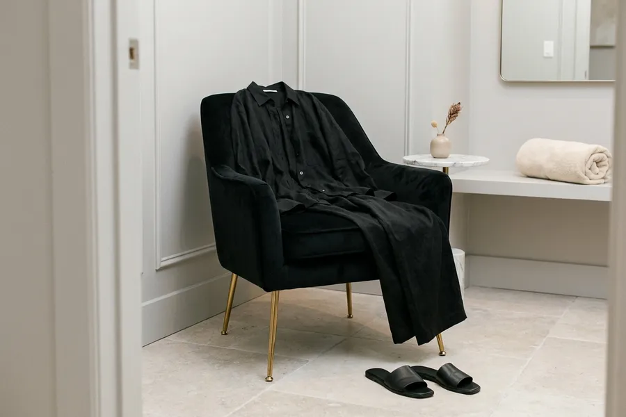 Loose black clothes and sandals laid on a velvet chair
