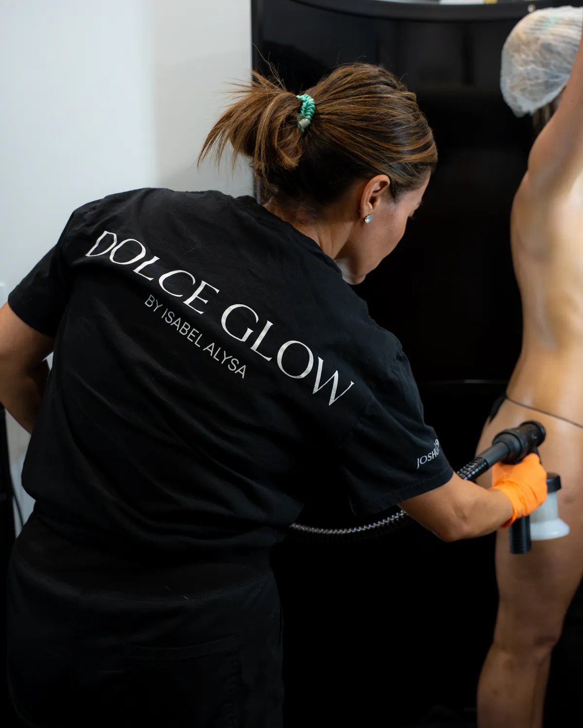 Faby Carr applying a Dolce Glow spray tan by hand in the tanning room at AWE